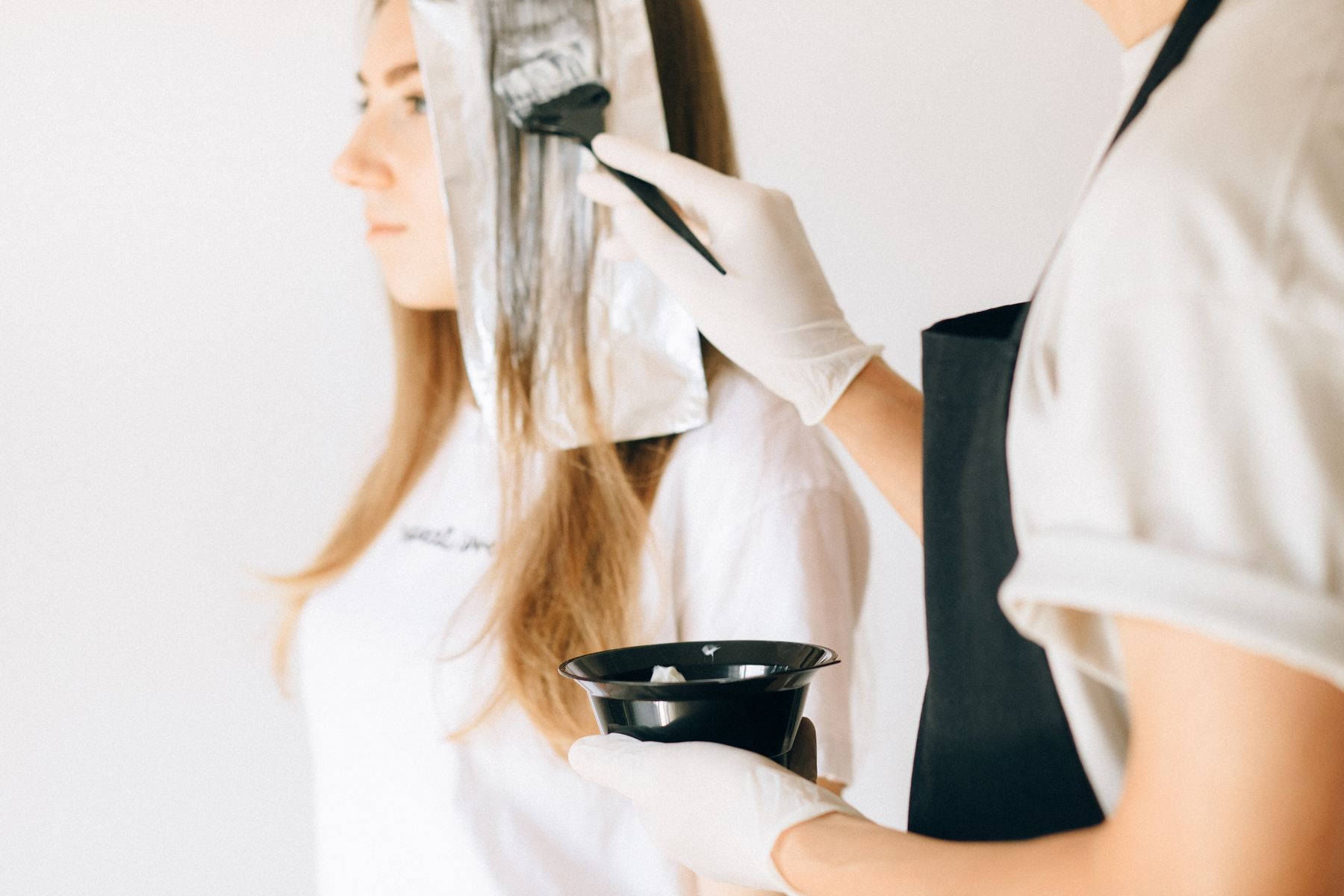 Hairdresser applying colour to a client's hair with brush and foil