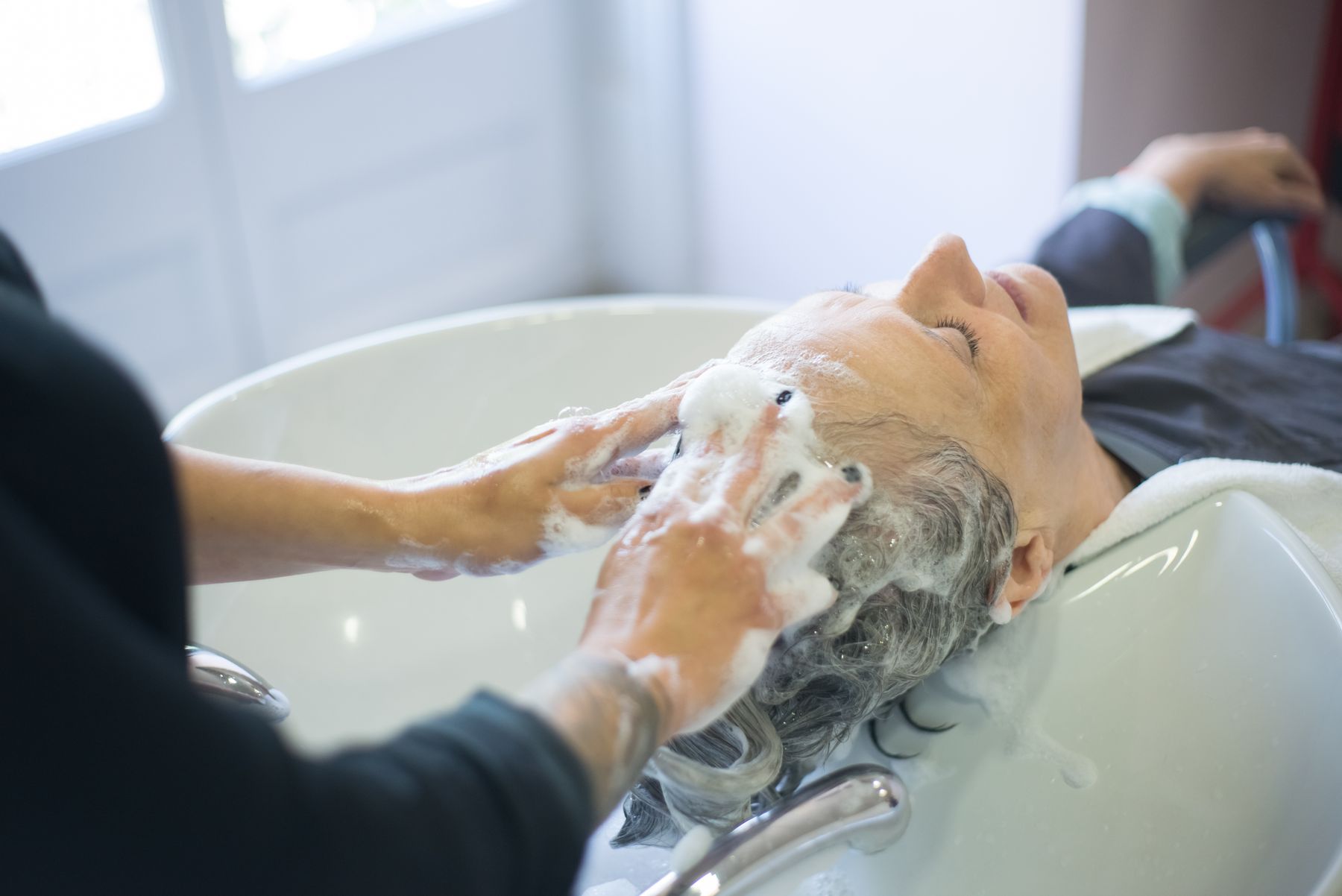 Client's hair being washed with foam at a salon basin